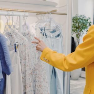 A customer in a yellow blazer browses stylish clothing in a chic boutique setting.