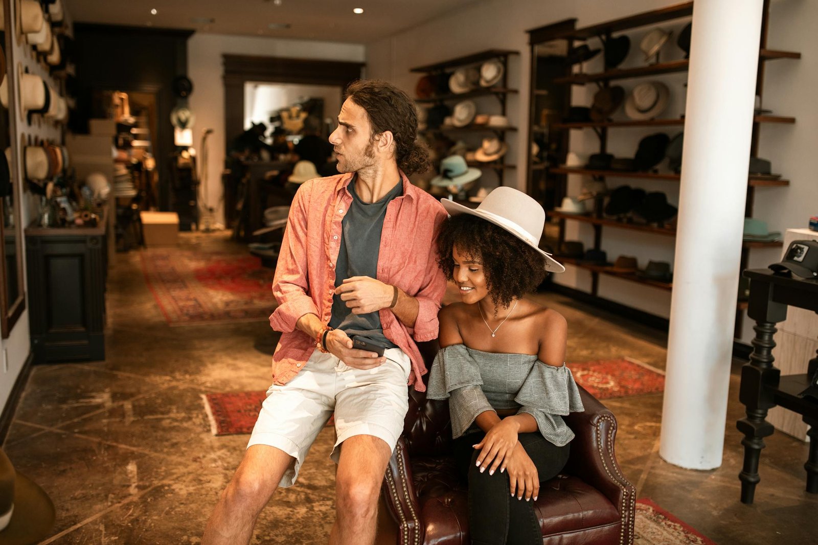A man and woman enjoying shopping in a stylish boutique, surrounded by hats.