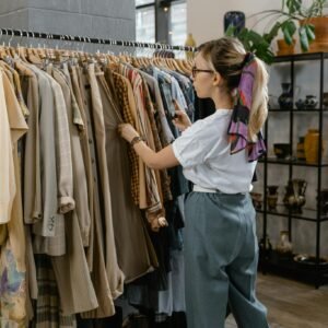 Woman browsing through clothes on hangers in a stylish boutique setting.