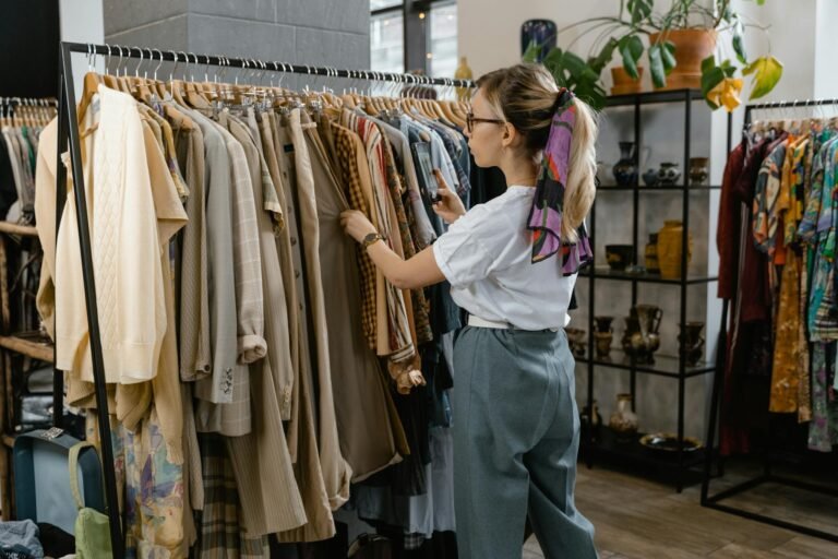 Woman browsing through clothes on hangers in a stylish boutique setting.