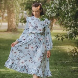 Woman in a flowing floral dress walking gracefully in a lush green park setting.